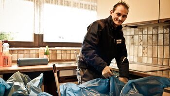 Mitarbeiter packt Müllsäcke in Küche